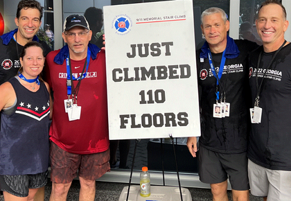 A group of people standing next to a sign that says, "Just Climbed 110 Floors"